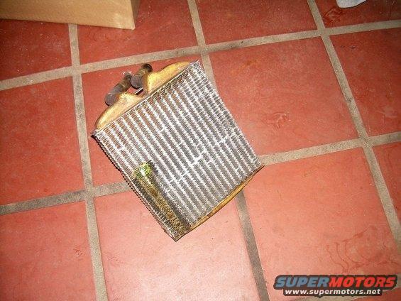 Heater core with two hose connections, resting on a tiled floor