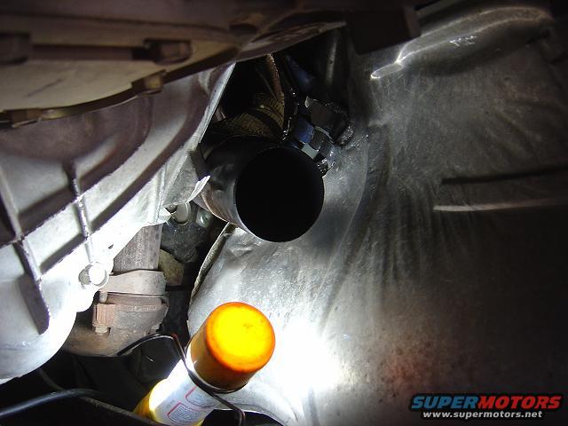 Close-up of vehicle exhaust pipe and transmission housing, with a yellow-capped spray can visible