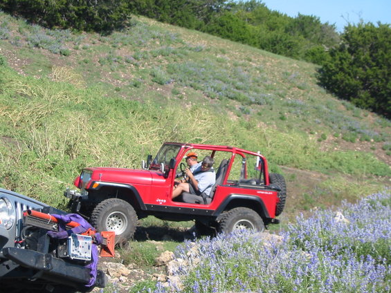 Red Jeep Wrangler driving off-road with another Jeep in the foreground