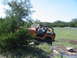 1996 Ford Bronco - Two people are off-roading in an orange Jeep Wrangler on a sunny day.