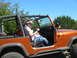 1996 Ford Bronco - A woman drives an orange Jeep Wrangler on a sunny day.