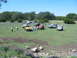 1996 Ford Bronco - A gathering of off-road vehicles and people in a scenic, grassy landscape under a clear blue sky.