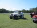 1996 Ford Bronco - A group of people stand around a white Jeep Wrangler Laredo, with other Jeeps visible in the background on a sunny day.