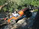 1996 Ford Bronco - An orange Jeep Wrangler navigates a rocky trail with occupants inside.