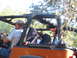 1996 Ford Bronco - People ride in an orange off-road vehicle, possibly a Jeep, on a sunny day.
