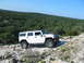 1996 Ford Bronco - White Hummer H2 navigates a challenging rocky terrain under a clear blue sky.