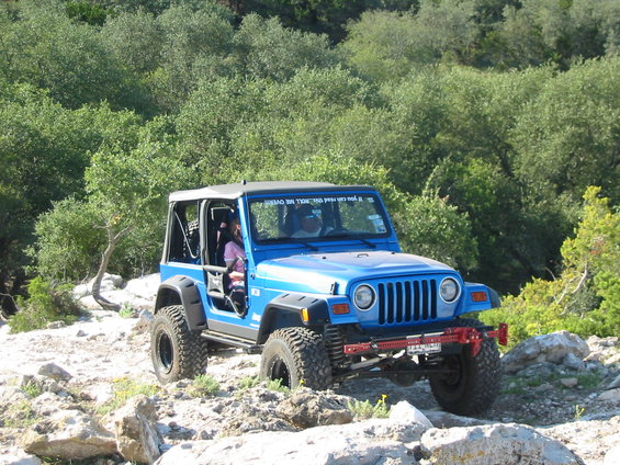 Blue Jeep Wrangler TJ off-roading on rocky terrain
