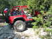 1996 Ford Bronco - A red Jeep Wrangler navigates a rocky trail, with a Texas flag attached to the spare tire.