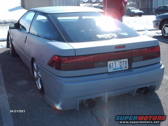 Rear view of light blue coupe with aftermarket body kit and dual exhaust pipes
