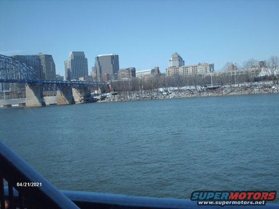 City skyline across a river with a bridge and snow on the banks