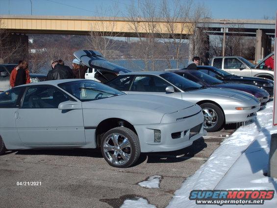 Gray coupe with gullwing doors, unfinished bodywork, chrome wheels, parked in snow