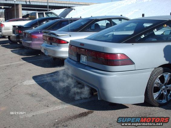 Rear view of a light gray 1995 Ford Probe with exhaust smoke