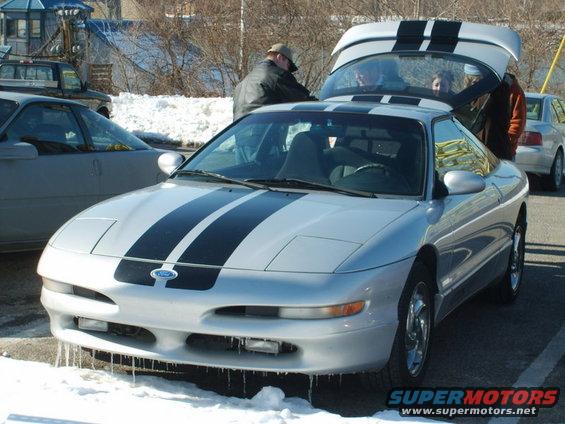 Silver 1995 Ford Probe with black racing stripes, front 3/4 view, snow on ground, trunk open