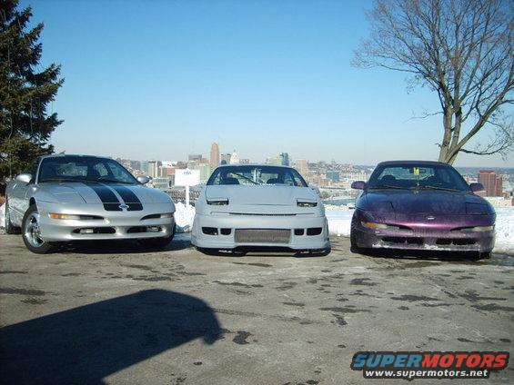 Three 1995 Ford Probes parked in front of a city skyline
