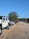 1996 Ford Bronco - A convoy of off-road vehicles, including a white Hummer and several Jeeps, are parked on a dirt path under a clear blue sky.