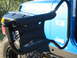 1996 Ford Bronco - A blue Jeep Wrangler is shown from the side, equipped with a black roll cage and padded grab handles.
