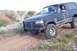 1995 Ford Bronco - A black Ford Bronco navigates a rough, off-road terrain with a prominent bull bar and lifted suspension.