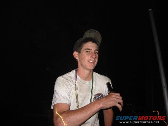 guy wearing beads and holding a beer bottle, wearing a cap backwards