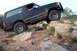 1995 Ford Bronco - This black SUV is navigating a rocky, off-road terrain with a driver visible.