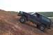 1995 Ford Bronco - A black 1995 Ford Bronco navigates a challenging incline on a dirt trail.