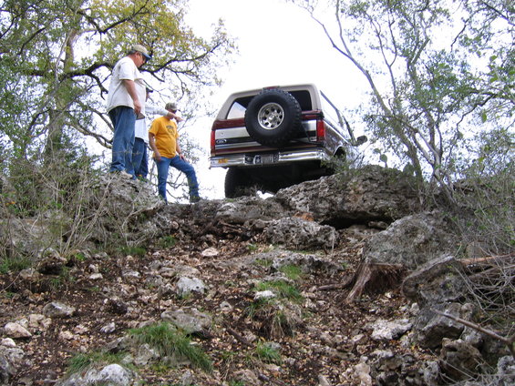 1996 Ford Bronco climbing rocky hill, spare tire on back