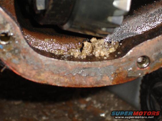 Differential housing showing rust and a buildup of light brown sludge