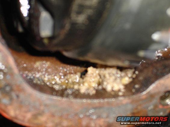 close-up of chunky, light-colored substance in rusty metal housing