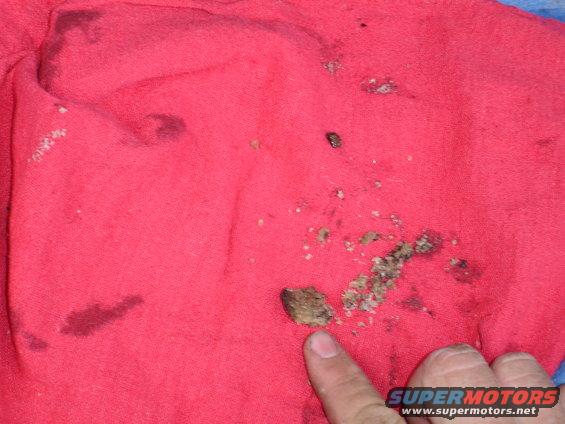 Red cloth with dirt, grease stains, and debris, pointed to by a finger