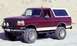 1993 Ford Bronco - This lifted Ford Bronco is parked on a dirt road with a sandy hill in the background.