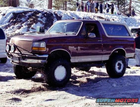 1993 Ford Bronco with aftermarket wheels and lights parked in snow