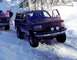 1993 Ford Bronco - A dark blue Ford Bronco is stuck in the snow, with a red truck nearby.