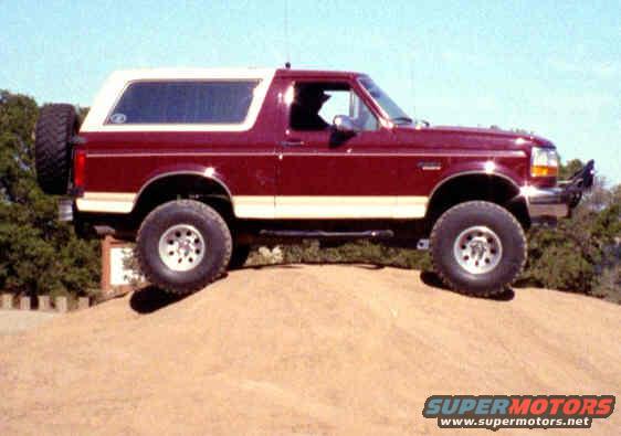 Red 1993 Ford Bronco side view with white top and spare tire