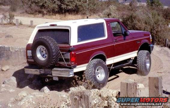 1993 Ford Bronco with spare tire mounted on rear, driving over rocks