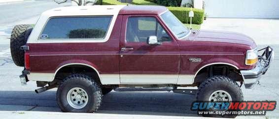 Maroon and white Ford Bronco with a spare tire on the back