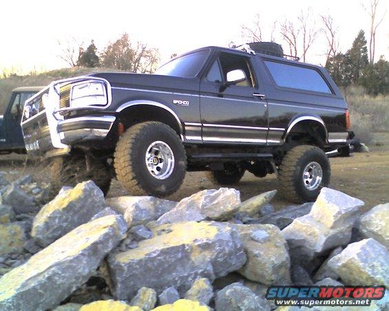 Black Ford Bronco with lifted suspension and off-road tires on rocks