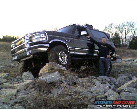 Guy next to black 1995 Ford Bronco on rocks