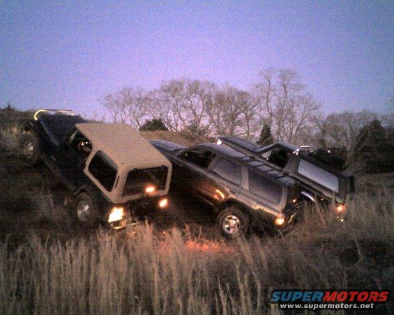 Three SUVs parked on a grassy incline at dusk