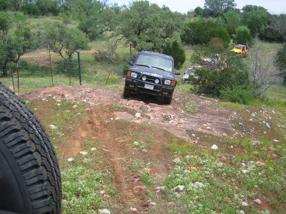 Land Rover Discovery navigating a rocky trail with other vehicles in the background