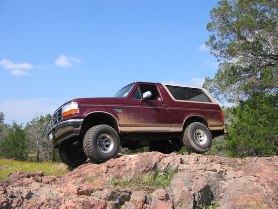 Maroon 1996 Ford Bronco climbing rocks