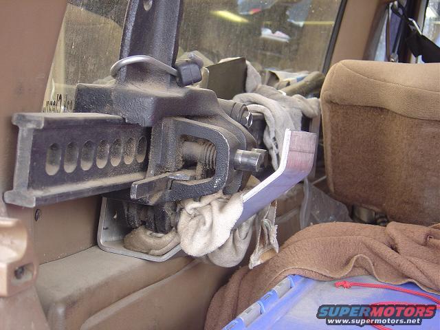 Hi-lift jack mounted on the interior panel of a vehicle, next to a tan seat and covered in dust