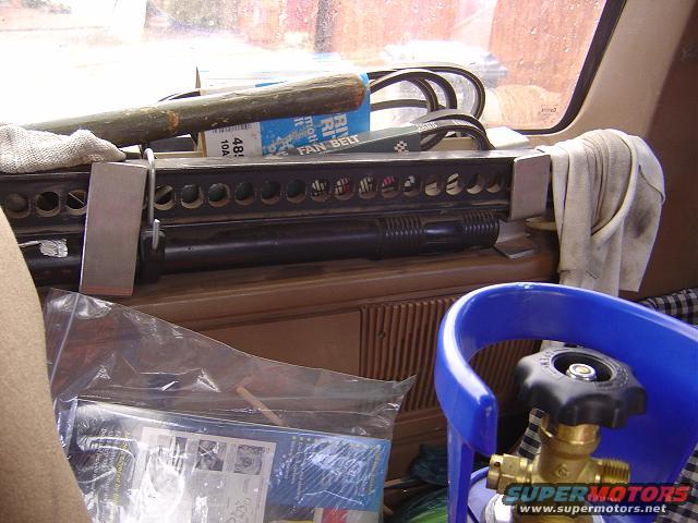 Interior view of a vehicle with a blue propane tank and a hi-lift jack