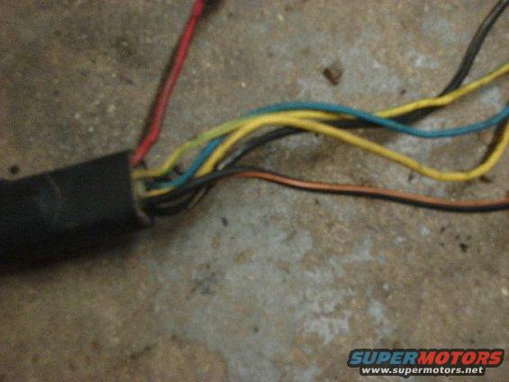 Close-up of a black automotive wiring harness with red, yellow, blue, and brown wires exposed