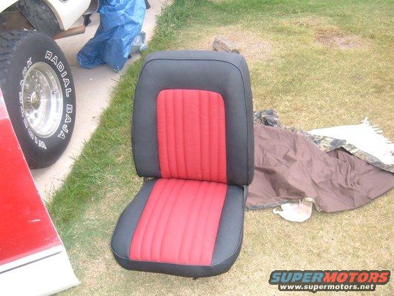 Car seat with red and black upholstery, next to a tire and red body panel