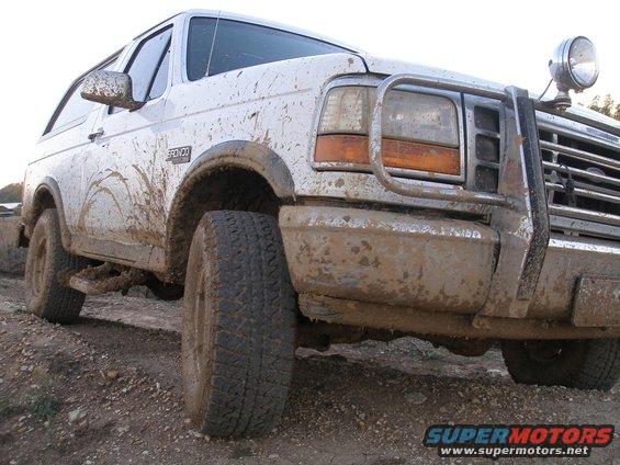 Mud-covered white 1992 Ford Bronco, front quarter view, with a brush guard and off-road tires