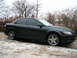 1994 Ford Probe - A black sedan is parked on a surface with patches of snow and ice, with trees in the background.