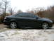 1994 Ford Probe - Side view of a dark sedan with five-spoke alloy wheels parked on a snowy surface.