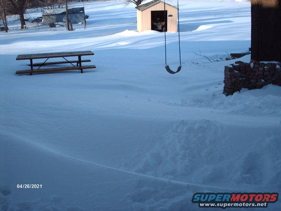 Snow-covered yard with picnic table, shed, and swing set. Date stamp 04/26/2021