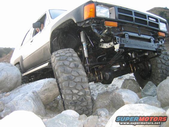 Front view of a 1985 Toyota 4Runner with large tires, navigating over large rocks