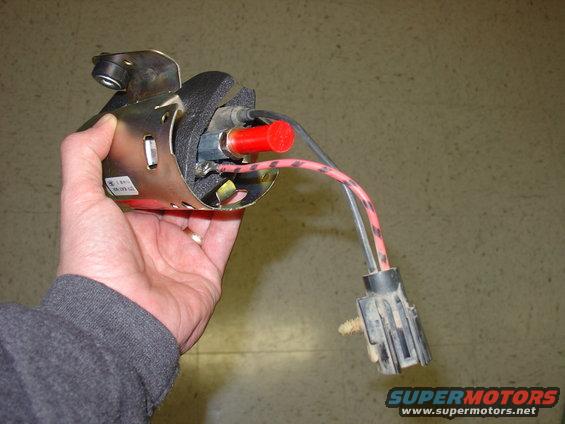 hand holding a fuel pump with red cap and electrical connector