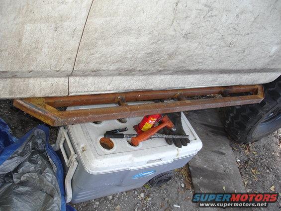 Side view of custom rock sliders on a vehicle, with tools on a cooler underneath